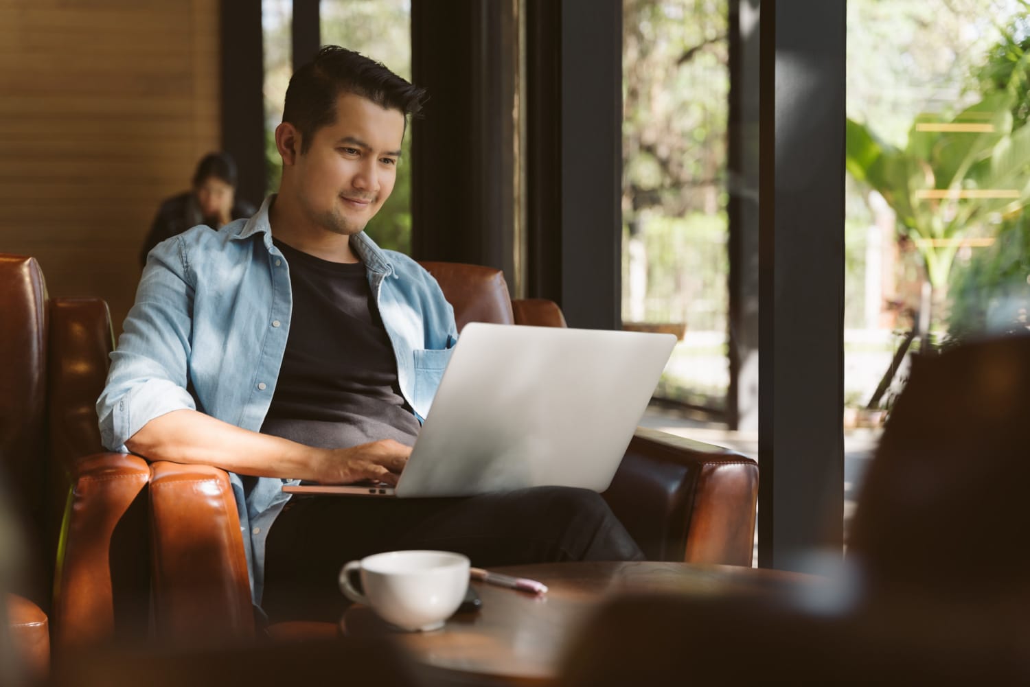 A freelancer bearded man in t-shirt taking notes at laptop in ca a freelancer bearded man in t shirt taking notes at laptop in ca